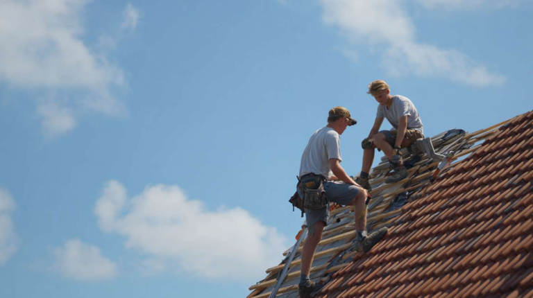 Contractors installing tar paper on a flat commercial roof, laying down overlapping sheets for waterproofing protection.